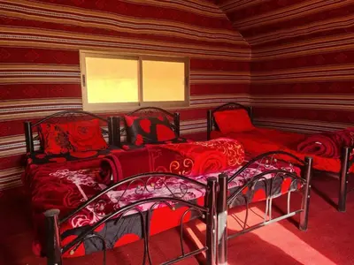 a bedroom with two beds and two chairs in a room at Wadi Rum Local Guide in Wadi Rum