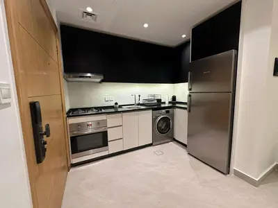 a kitchen with stainless steel appliances and black cabinets at Damac Tower Amman - Luxury Studio - استوديوهات فاخرة - داماك عمان العبدلي in Amman