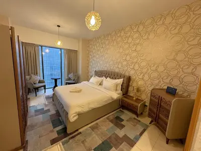 a bedroom with a bed and a chair and a window at Damac Tower Amman - Luxury Studio - استوديوهات فاخرة - داماك عمان العبدلي in Amman