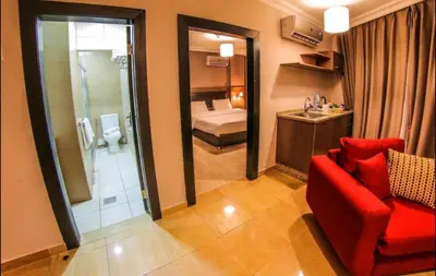 a room with a red chair and a bathroom at Ibiza Hotel in Amman