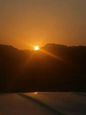 a sunset over a body of water with the sun in the sky at The sun of Wadi Rum in Wadi Rum