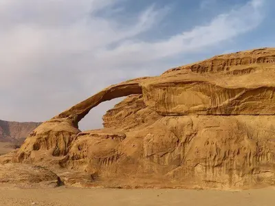 a brown rock formation in the desert with a sky at The sun of Wadi Rum in Wadi Rum