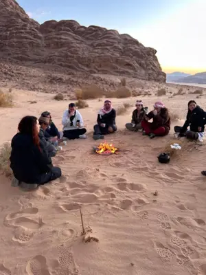 a group of people sitting on the sand in the desert at Bedouin Desert Life Camp & Jeep Tours in Wadi Rum
