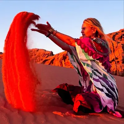 a woman is sitting in the desert with a creature at Bedouin Desert Life Camp & Jeep Tours in Wadi Rum