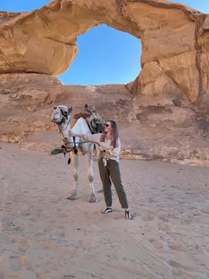 a woman standing next to a camel in the desert at Bedouin Desert Life Camp & Jeep Tours in Wadi Rum