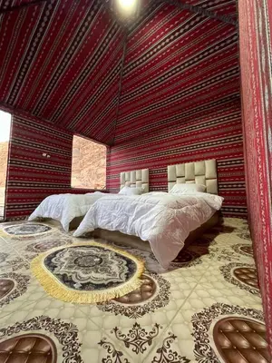 a bedroom with a large bed with a red wall at Adam Bedouin camp in Wadi Rum