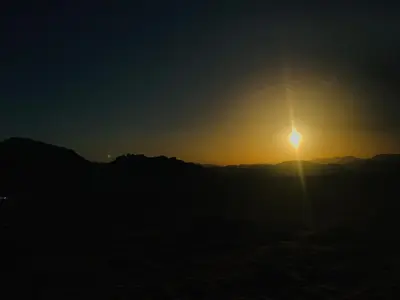 a sunset over the mountains with the sun in the sky at Wadirum Zeid Classic camp in Wadi Rum
