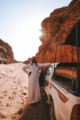a woman standing next to a vehicle in the desert at Wadirum Zeid Classic camp in Wadi Rum