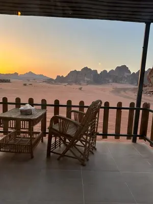 a table and chairs on a balcony with a view of the desert at Wadi Rum Star Camp in Wadi Rum