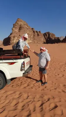 a man standing in the desert next to a truck at Enad desert camp in Wadi Rum