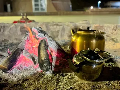 a pot and a tea kettle sitting next to a fire at Jabal Rum Camp in Wadi Rum