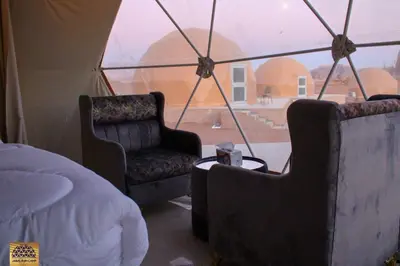 a room with two chairs and a bed and a window at Jabal Rum Camp in Wadi Rum
