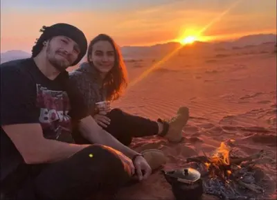 a man and a woman sitting next to a fire at Wadi Rum Desert Stars in Wadi Rum