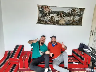two men sitting on a bed with luggage at Beit alkaram in Kerak