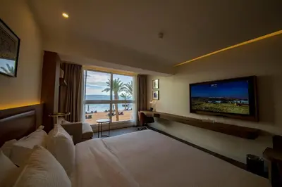a hotel room with a large bed and a television at Luxotel Aqaba Beach Resort & Spa Only 15 years plus in Aqaba