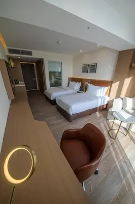 a hotel room with two beds and a chair at Luxotel Aqaba Beach Resort & Spa Only 15 years plus in Aqaba