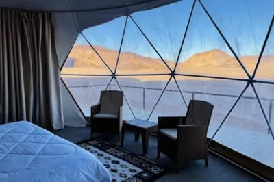 a room with a bed and chairs and a large window at Wadi Rum beautiful time in Wadi Rum