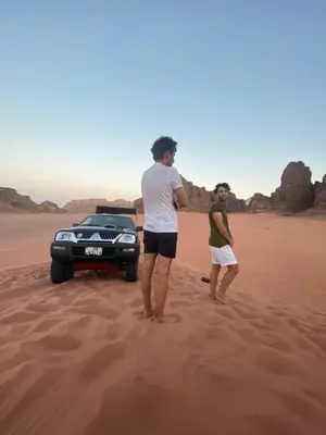 two men standing in the sand near a car in the desert at Wadi Rum beautiful time in Wadi Rum