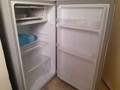 an empty refrigerator with its door open and a bottle of water in it at Aun Wadi Rum Camp in Wadi Rum