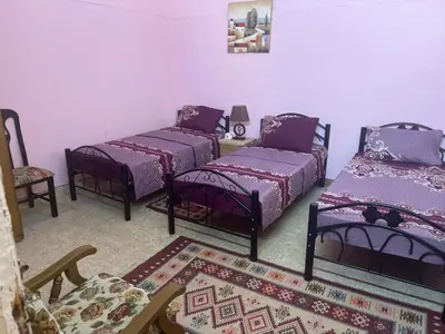 a room with four beds and a chair and a rug at IBN Khaldoon in Madaba