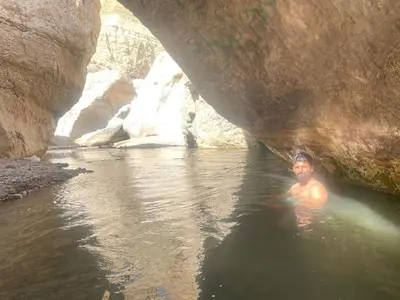 a man swimming in a river under a bridge at 7 Caves Hotel in Al Jāyah