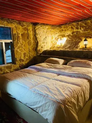 a bedroom with a large bed in a stone wall at 7 Caves Hotel in Al Jāyah