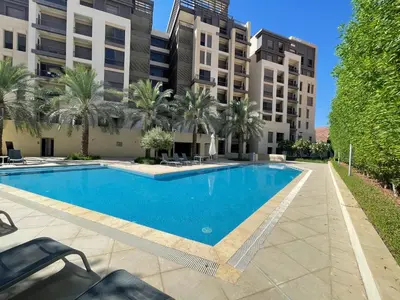 a swimming pool with palm trees and buildings at Al Raha Village - Aqaba in Aqaba