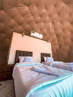 a bedroom with two beds with a comforter and a ceiling at Star Magic Camp in Wadi Rum