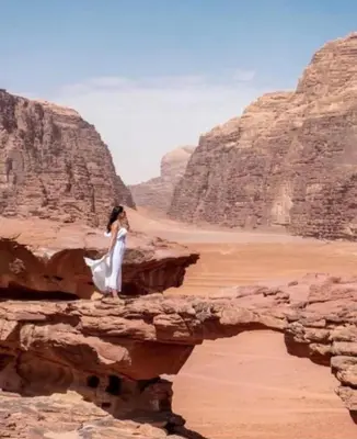 a woman standing on a rock in the desert at Star Magic Camp in Wadi Rum