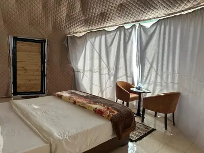 a bedroom with a bed and a window and a table at Night Magic Camp in Wadi Rum