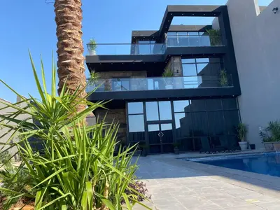 a house with a glass facade and a palm tree at laperla chalet villa di lusso deadsea in Sowayma