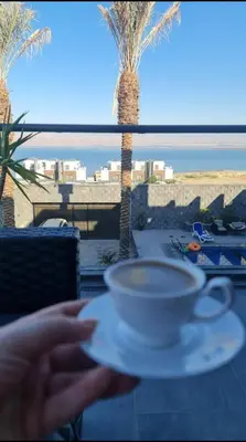 a cup of coffee on a table with a palm tree at laperla chalet villa di lusso deadsea in Sowayma