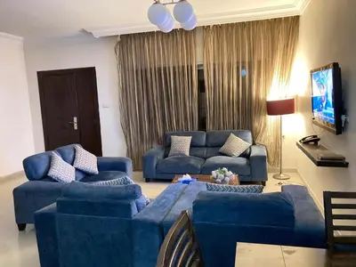 a living room with two blue couches and a tv at Uptown Hotel Apartment in Amman