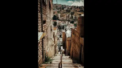 a person walking down an alleyway between two buildings at The Royal Luxury Superior Queen cot in Amman