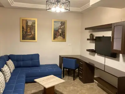 a living room with a blue couch and a tv at The Royal Luxury Superior Queen cot in Amman