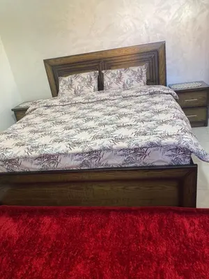 a bed with a red rug in a bedroom at Jerash air apartment in Jerash