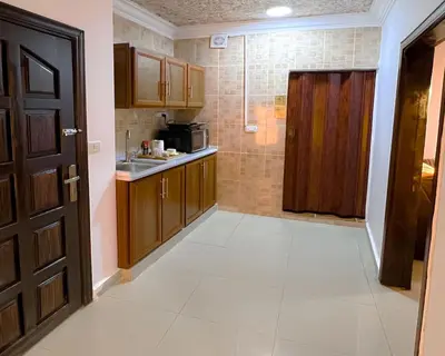 a kitchen with wooden cabinets and a door in a room at Petra Cloud 1977 in Wadi Musa