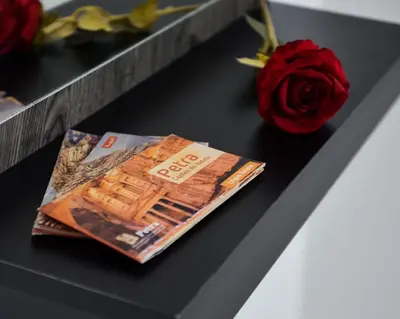 a magazine sitting on a table next to a rose at Petra Cloud 1977 in Wadi Musa