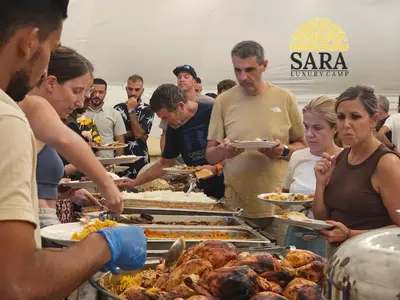 a group of people standing around a buffet of food at SARA lUXURY CAMP in Wadi Rum