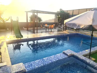 a swimming pool with a table and an umbrella at Zoom Chalets in Amman
