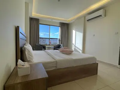 a bedroom with a large bed and a large window at Aster Hotel Aqaba in Aqaba