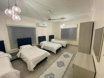 a room with four beds and a table and lights at Lovely 3-bedrooms rental unit in Aqaba