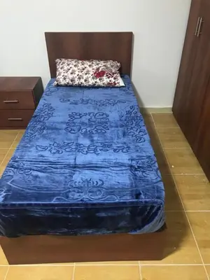 a bed with a blue comforter on it in a room at Elite Furnished Apartment in Wadi Musa