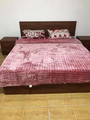 a bed with a pink comforter on top of it at Elite Furnished Apartment in Wadi Musa