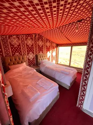 two beds in a room with a red ceiling at Obeid's Bedouin Life Camp in Wadi Rum