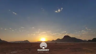 a view of the sun setting in the desert at Harmony Luxury Camp in Wadi Rum