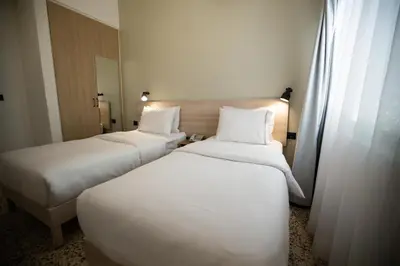 two beds in a hotel room with white sheets at Julia's Hotel Suites in Amman