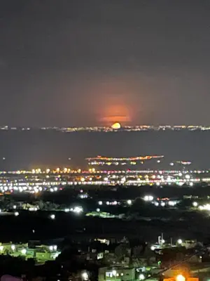 a view of a city at night with the moon at Villa Jana Chalet in Ash Shāghūr