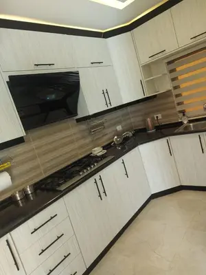 a kitchen with white cabinets and black counter tops at Villa Jana Chalet in Ash Shāghūr