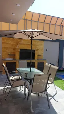 a table and chairs with an umbrella over it at Villa Jana Chalet in Ash Shāghūr